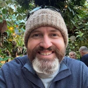 Coach Brandon Jenkins is pictured wearing a tan hat and smiling. He writes about leaders coming to coaching.