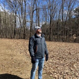 Coach Brandon Jenkins writes about the power of and. He is pictured outdoors, wearing a coat and looking at the sky.