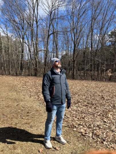 Coach Brandon Jenkins writes about the power of and. He is pictured outdoors, wearing a coat and looking at the sky.