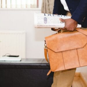 adeolu-eletu-wN3iop4-j3A-unsplash Author and Coach, Brandon Jenkins, writes about helping your team trust you. Image shows a person leaning against a wall, holding a newspaper and messenger bag.