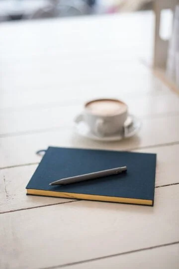 Journal and coffee on a table, symbolizing reflection.