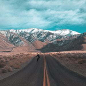 brad-mills-9sgdhwtLOR8-unsplash Man skateboarding and enjoying life on a highway with mountains in the distance