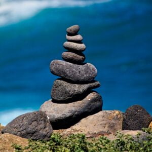 dusan-veverkolog-mX2mdxhc0UM-unsplash A small rock cairn against a blue ocean backdrop.
