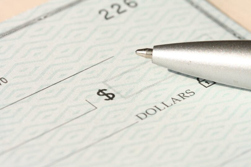 Blank check with pen sitting on top.